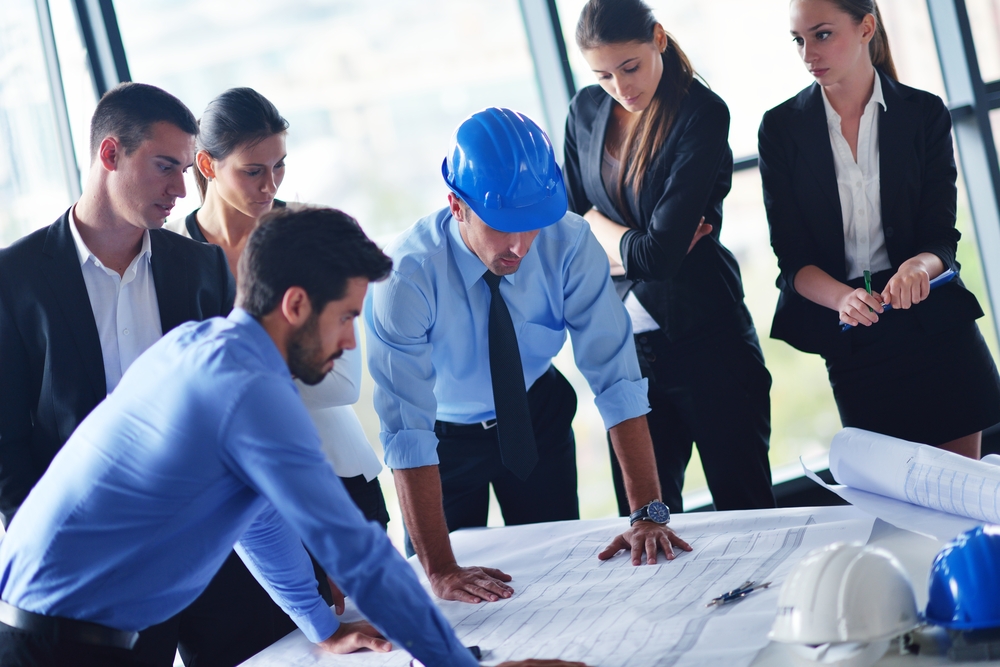A team of engineers reviews blueprints